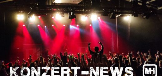 Bild von einem Publikum vor einer Bühne in rotem Licht.