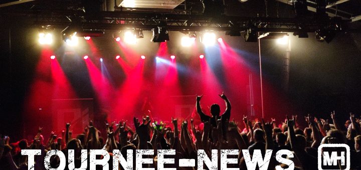 Ein Bild mit einer Menge vor einer Bühne in rotem Licht.