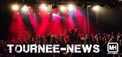 Ein Bild mit einer Menge vor einer Bühne in rotem Licht.