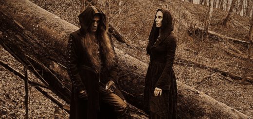 Das Duo WitcheR in schwarzer Kleidung im Wald. Beide habend die Kapuzen über dem Kopf und blicken in verschiedene Richtungen.