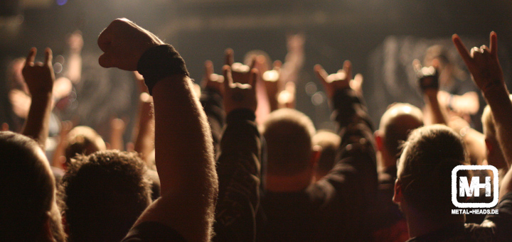 Ein Metalkonzert-Publikum streckt die Hände in die Höhe.