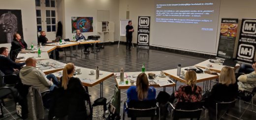 Menschen, Marken, Moshpits: Blick auf das im Halbkreis sitzende Publikum. Ein Referent blickt auf seine Präsentation.