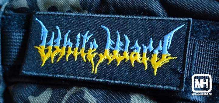 White-Ward-Aufnäher in den Landesfarben der Ukraine auf einem camouflage-farbenen Rucksack (Detailaufnahme)