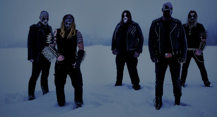 Die Band Nattverd steht mit Corpse Painting und Klamotten mit gewaltigen Nieten und Patronengürteln im Schnee.