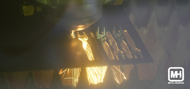 Metalgabeln werden geschnitten: Durch den Funkenflug wird die Metallplatte von hinten beleuchtet und man sieht die Konturen der ausgeschnittenen Metalgabeln.