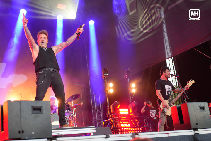 Papa Roach live auf dem Vainstream 2023: Sänger Jacoby Shaddix wirft die Arme in die Luft. Im Hintergrund die übrigen Bandmitglieder.