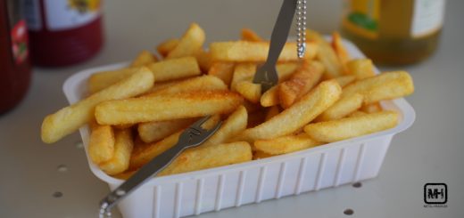 Eine Kunststoff-Schale Pommes mit zwei Metalgabeln.
