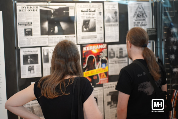 Menschen stehen in der Ausstellung "Der Harte Norden" vor einer Schauwand mit Zeitungsartikeln.
