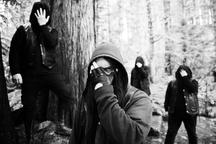 Uada stehen im Wald. Die Bandmitglieder halten sich mit den Händen die Augen zu.
