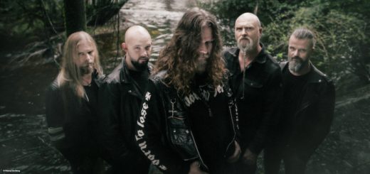 Borknagar im Gruppenbild vor einem Bach im Wald. Die Kamera blickt von schräg oben auf die Bandmitglieder herab.