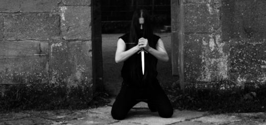 Duindwaler: Der Solomusiker kniet im Eingang einer alten Ruine und hält mit beiden Händen einen Dolch mit der Spitze nach unten.