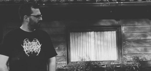 S.J. von Tiefstand vor einer Holzhütte.