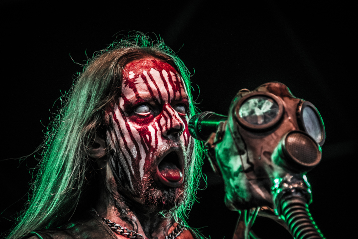 Helmuth von Belphegor auf dem Motocultor Festival 2014 mit blutverschmiertem Gesicht und fahlen Augen vor einem Mikroständer mit Gasmaske.