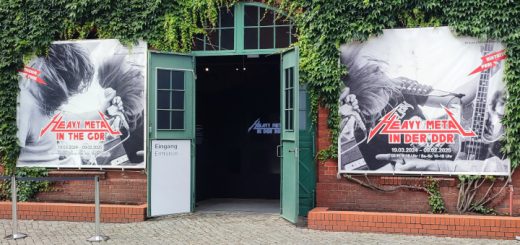 Blick auf den Eingangsbereich der Ausstellung "Heavy Metal in der DDR". Links und rechts der alten Türe des Backsteingebäudes hängen die Plakate der Ausstellung.