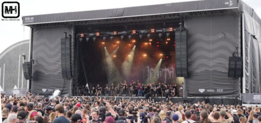 Blick auf die Bühne des Elbriot 2024: Neaera haben etwa eine große Menge Fans auf die Bühne geholt. Das Foto ist aus der Entfernung geschossen und zeigt die ganze Bühne und das davor feiernde Publikum.