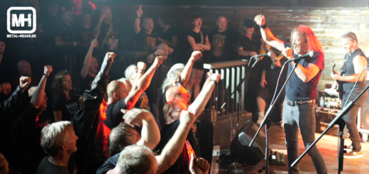 Flotsam and Jetsam live in Bochum 2024: Der Sänger reckt die Faust und das Publikum tut es ihm gleich. Das Bild ist aus der Entfernung rechtwinklig zu Bühne und Publikum aufgenommen.