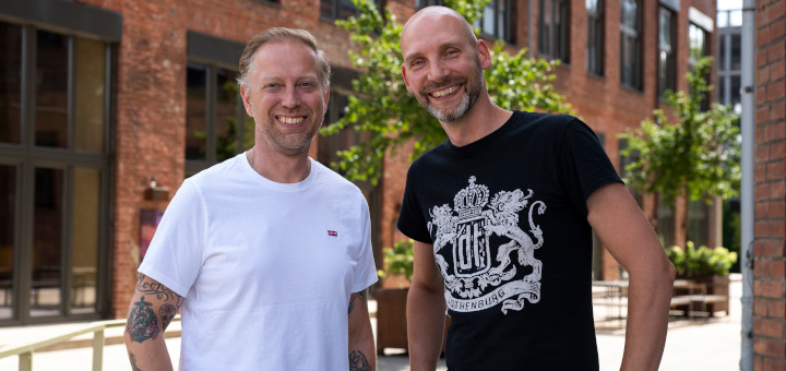 Tom Naber und Prof. Dr. Matthias Johannes Bauer von der IST-Hochschule für Management vor einem alten Industrie-Bauwerk.