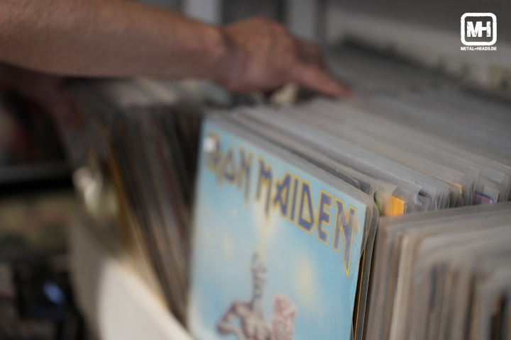 Blick in einen Plattenladen. Nahaufnahme einer Hand, die durch das Angebot blättert. Erkennbar ist unscharf das Albumcover von "Seventh Son of a Seventh Son" von Iron Maiden.