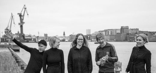 Bandfoto mit ausgelassenen Gesten vor einer Hafensituation