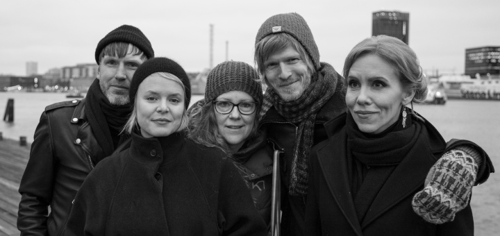 Bandfoto in Schals und Mützen vor einer Hafensituation