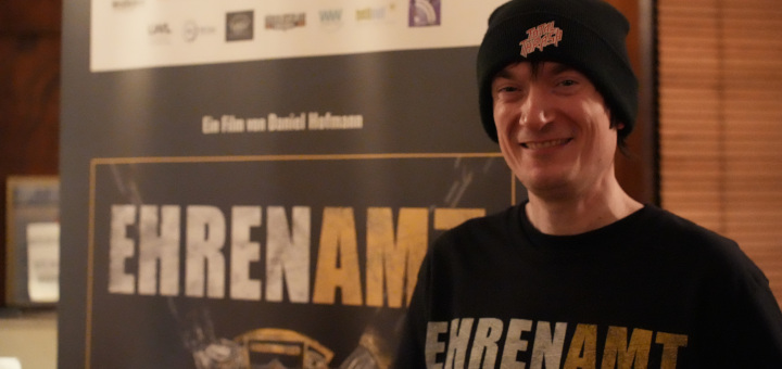 Regisseur Daniel Hofmann vor einem Roll-Up zum Film "Ehrenamt"