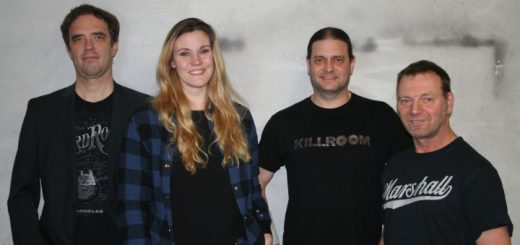 Die Bandmitglieder stehen vor einer Betonmauer.