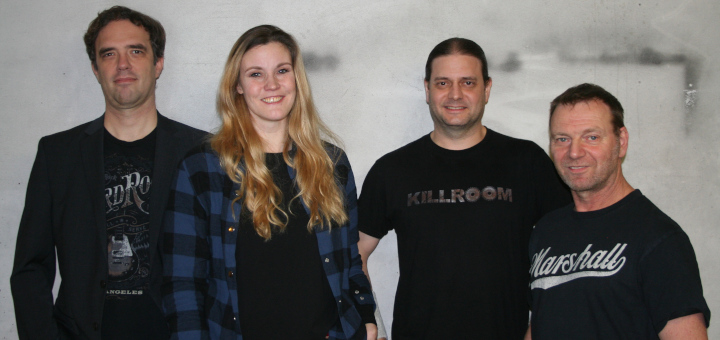 Die Bandmitglieder stehen vor einer Betonmauer.