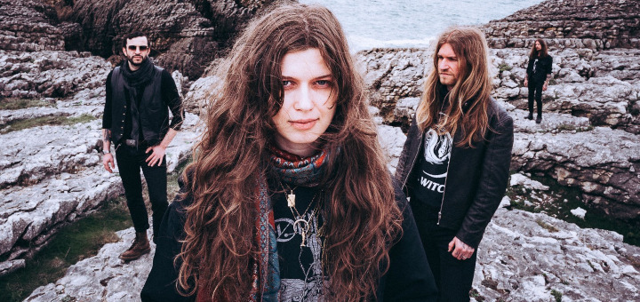 Coltaine-Bandmitglieder an einem steinigen Ufer.